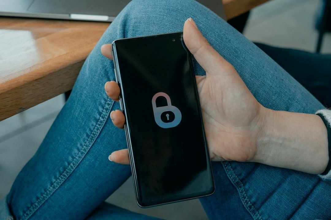 Hånd holder en smarttelefon med et låst hengelåsikon på skjermen